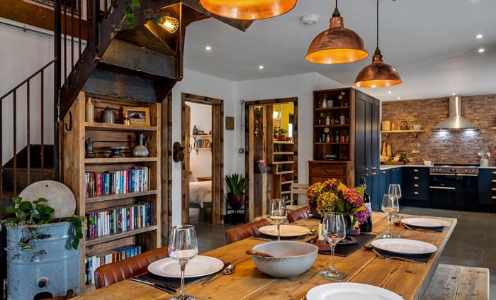 Large reclaimed wooden table seating 6, copper pendant lampshades, bookcase and reclaimed timber shelving, open plan into the large modern kitchen, fe